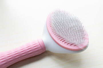 Closeup to a pink grooming cat brush with soft wool