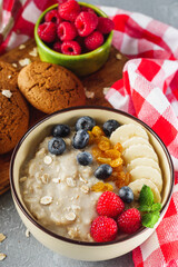 tasty nutritious oatmeal with fruits and berries on a light stone background