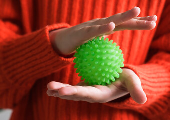 Children's hands hold massage ball. Therapeutic sensory activities for children's hands, neuropsychology, orthopedic correction. Child performs an exercise on tactile sensations on hand motor skills.