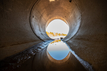 Inside a circular concrete drainage culvert with a trickle of water