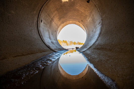 Inside a circular concrete drainage culvert with a trickle of water
