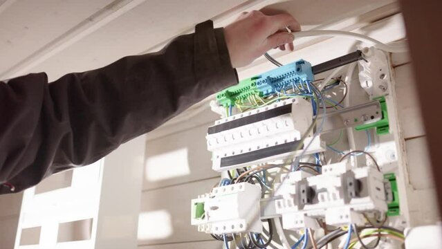 Electrician placing loose wires in electric panelboard before connecting them