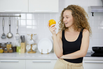 young woman smiling and holding orange in the kitchen