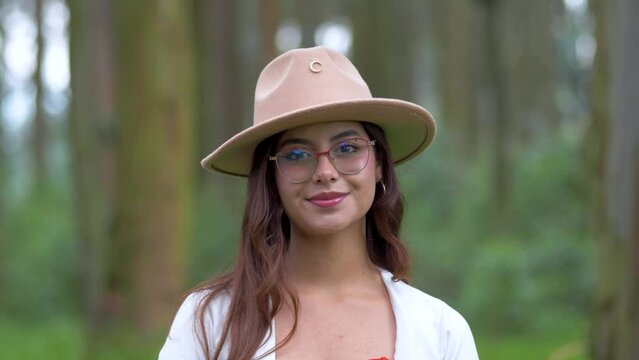 Charming smile of a young Ecuadorian girl in a hat. Sudden opening of eyes with pleasant surprise. Portrait shot with nature background