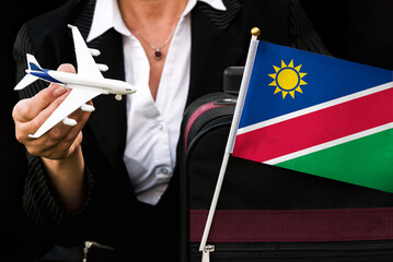 business woman holds toy plane travel bag and flag of Namibia
