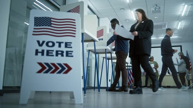 Vote here sign on the floor. Diverse American citizens vote in booths in polling station office. National Elections Day in the United States. Political races of US presidential candidates. Civic duty.
