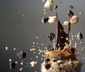 Foto op Plexiglas anti-reflex Creative food template. Chocolate syrup and bar chunk, seed cereal grains, flakes pouring drip over a glass pile of oat wheat muesli breakfast on grey background. copy text space   © Sandra Chia