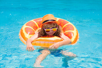 Child in sunglasses and summer hat floating in pool. Child having fun in summertime. Summer holidays and vacation with kids. Happy little boy playing in swimming pool outdoor on hot summer day. - 786834492