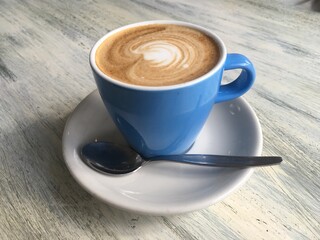 Cup of coffee in a blue cup white saucer.