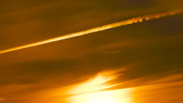 Slow zoom in to deep yellow golden hour sunset sky with plane contrail line