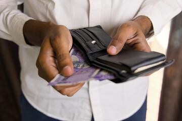 Close up of a man holding a wallet and Indian money in his hands