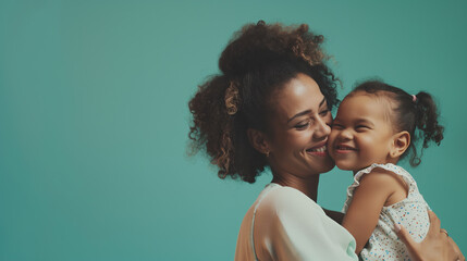 The camera focuses on Happy mother having fun with her daughter on teal color background professional photography.