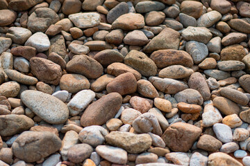 Gray sand and stones close-up on the beach. Stone in the foreground.