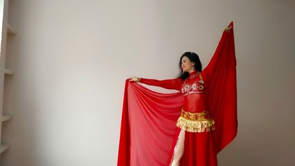 A dancer in a red suit is dancing with a red shawl an oriental dance on a white background. Free...