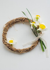Spring, concept. Yellow, white daffodil flowers in a wooden wicker frame, wreath on a white background. Background, postcard, place for text, top view, copy.
