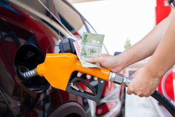 A person is filling up their car with gas and paying with cash. Concept of responsibility and practicality.