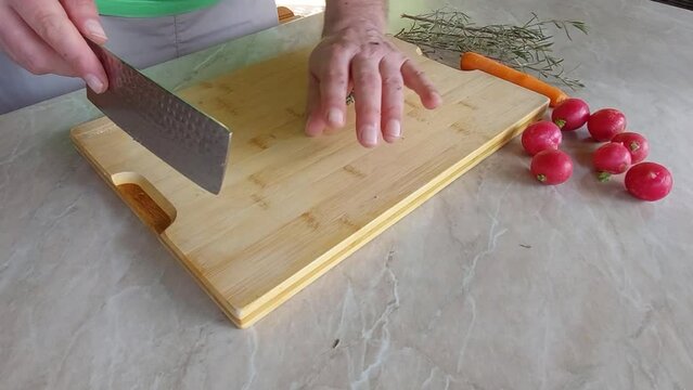 Cuting Fresh Rosemary on wooden board with Japanese ryukiri nikiri knife