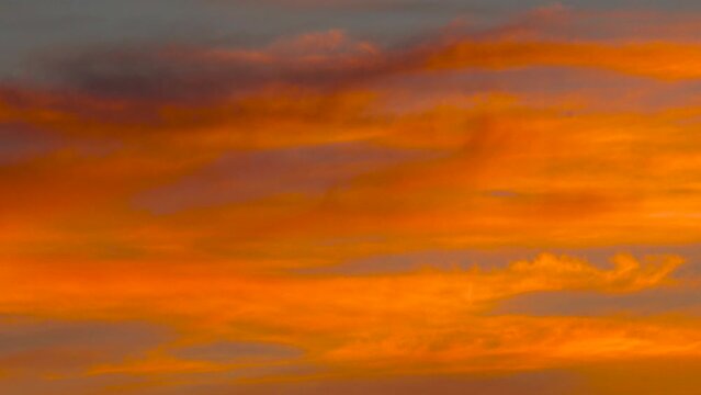 Slow zoom in into deep orange cloud formation during colorful sunset, Latvia