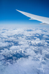 Aerial view through porthole of plane to of snow-covered mountain. Scenic view through aircraft....