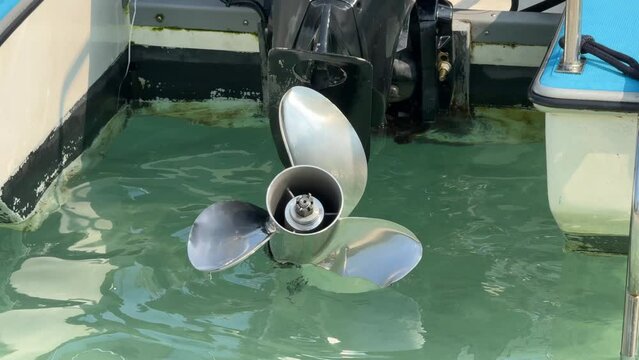 Close up stainless steel motor boat propeller on turquoise sea water background.