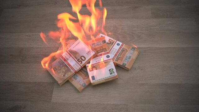 A man burns wads of euro bills on a wooden floor. The concept of inflation and devolution, the depreciation of money, the global crisis.