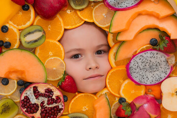 Funny fruits. Kids face with mix of strawberry, blueberry, strawberry, kiwi, dragon fruit, pomegranate, orange and melon. Assorted mix of fruits near child face. - 786864602