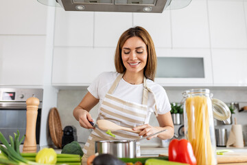 Joyful Young Lady Cooking and Sampling Dinner in a Pot, Present in a Contemporary Home Kitchen. Homemaker Preparing Nutritious Meal with a Smile. Domestic Life and Nourishment. Healthy Eating.