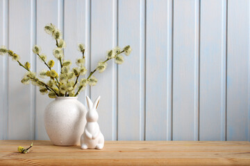 Easter background with an Easter bunny figurine and flowering willow branches on the table. Spring....