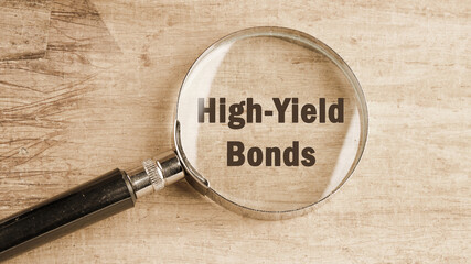 Inscription High-Yield Bonds visible through a magnifying glass on an old faded background