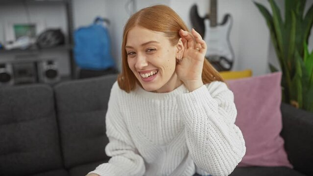 Hushed secrets! young redhead woman at home, sweater-wearing, hand over ear, hearing rumored gossip. deafness struggles indoors.