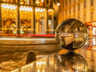 Weihnachtlicher Michaelerplatz in Wien spiegelt sich in Glaskugel, goldene Lichter erzeugen...