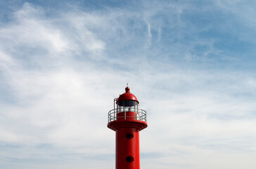 View of the red lighthouse against the cloudy sky