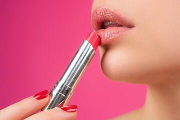 Applying lipstick. Painting lips with bright lipstick, close up. Pampering, lips correction...
