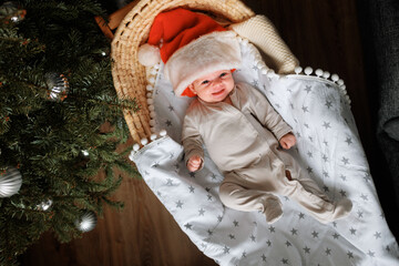 The newborn is lying in a cradle, wearing a Santa Claus hat.
