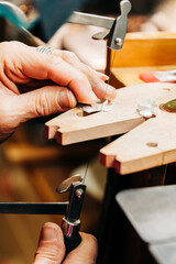 Close up shot of jewelers hands using jewelers saw