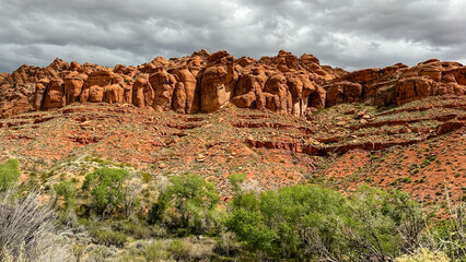 Red rock cliffs among green sagebrush on a cloudy day
