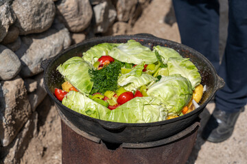 A person is cooking a large pot of vegetables, including cabbage