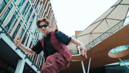 Low angle of asian attractive hipster pose at camera surround by mall. Portrait of break dance...