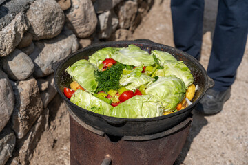 A person is standing next to a large pot of food