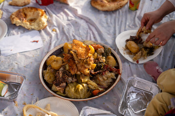 A plate of food is on a table with a person reaching for it