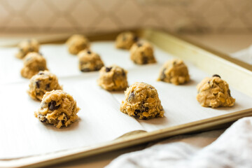 Cookie dough scoops with chocolate chips on baking sheet