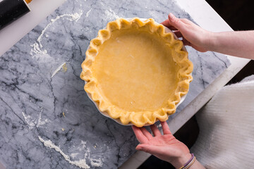 Preparing a fluted pie crust on a marble countertop