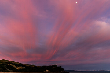 Beach with pink sunset and moon in Nelson, New Zealand