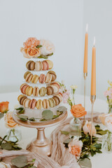 Macaroon Tower Closeup with Flowers and Lit Orange Candles