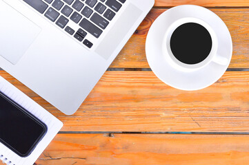 Modern white office desk table with laptop, notepad, smartphone and other supplies with cup of coffee. Top view, flat lay. Creative desk concept.