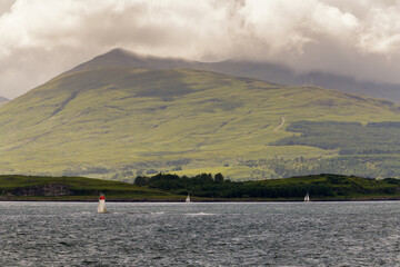 Petit phare blanc et rouge avec vue sur les montagnes de l'île de Mull en Ecosse © Joachim Beauvilain