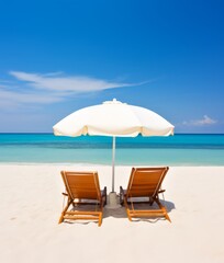 Two lounge chairs under an umbrella on a sandy beach by the ocean