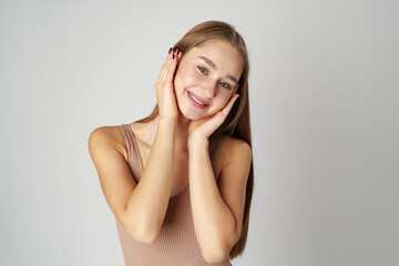 Woman Posing With Hands on Face against gray background