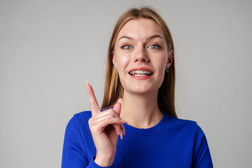 Young Woman Gesturing With Her Finger While Speaking Against a Gray Background