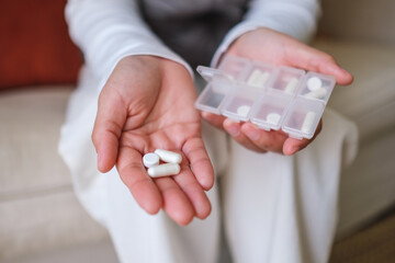 Closeup image of a woman holding pills and pillbox - 786900212